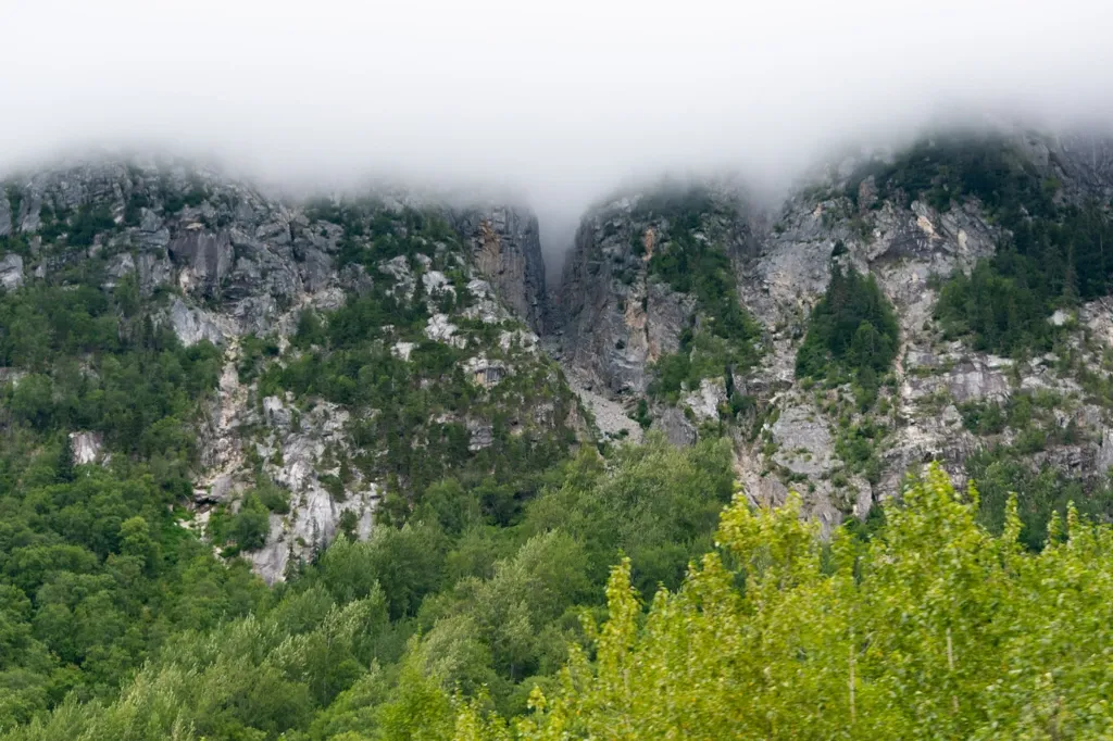 Photo of cliffs hugged by clouds on White Pass Railway